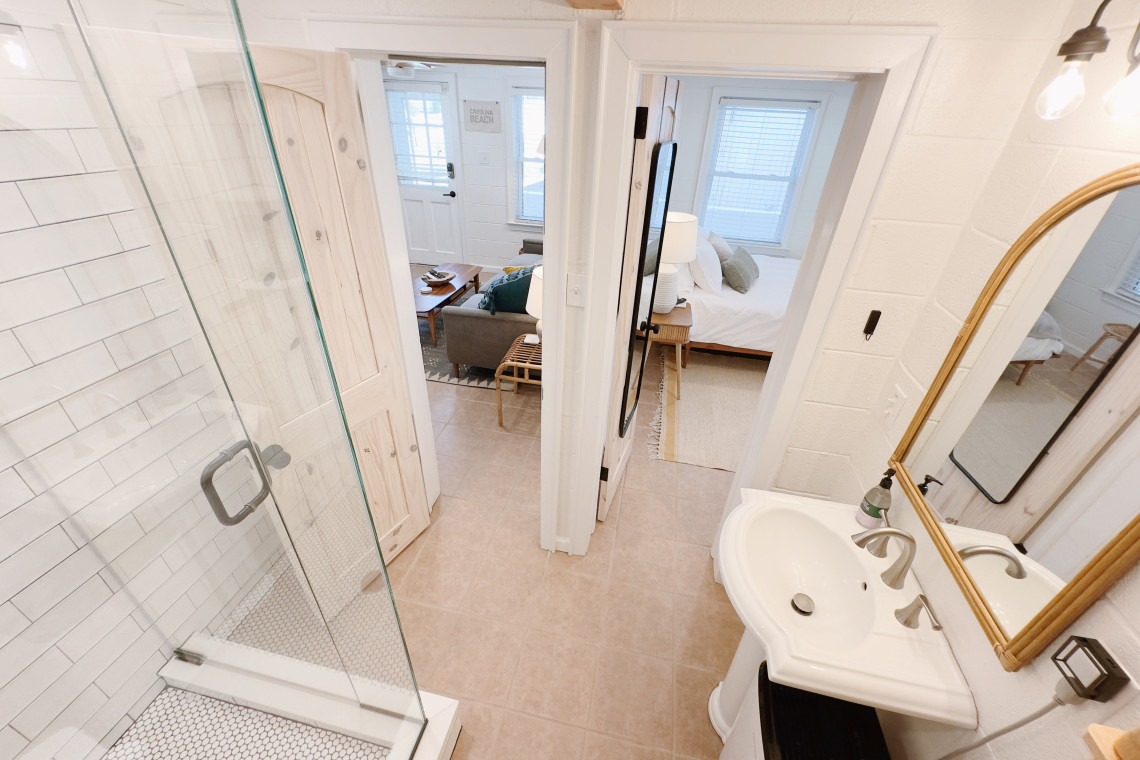The bathroom serves as a functional yet elegant connector between the living room and bedroom, seamlessly blending the two spaces together while providing privacy and convenience